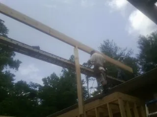 Carpenter setting a ridge beam over a new addition frame — Ice Dam Removal by Roofing Brothers in Cranston