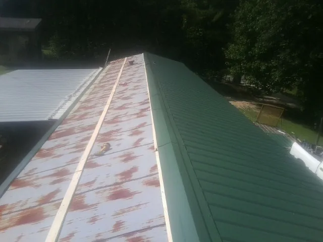 Old rusted panels beside newly installed green metal roofing — Wind Damage Roof Repair by Roofing Brothers in Cranston