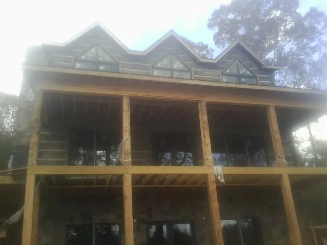 Dormers and porch framing on a large log home under construction — Roof Coating work by our crew in Cranston