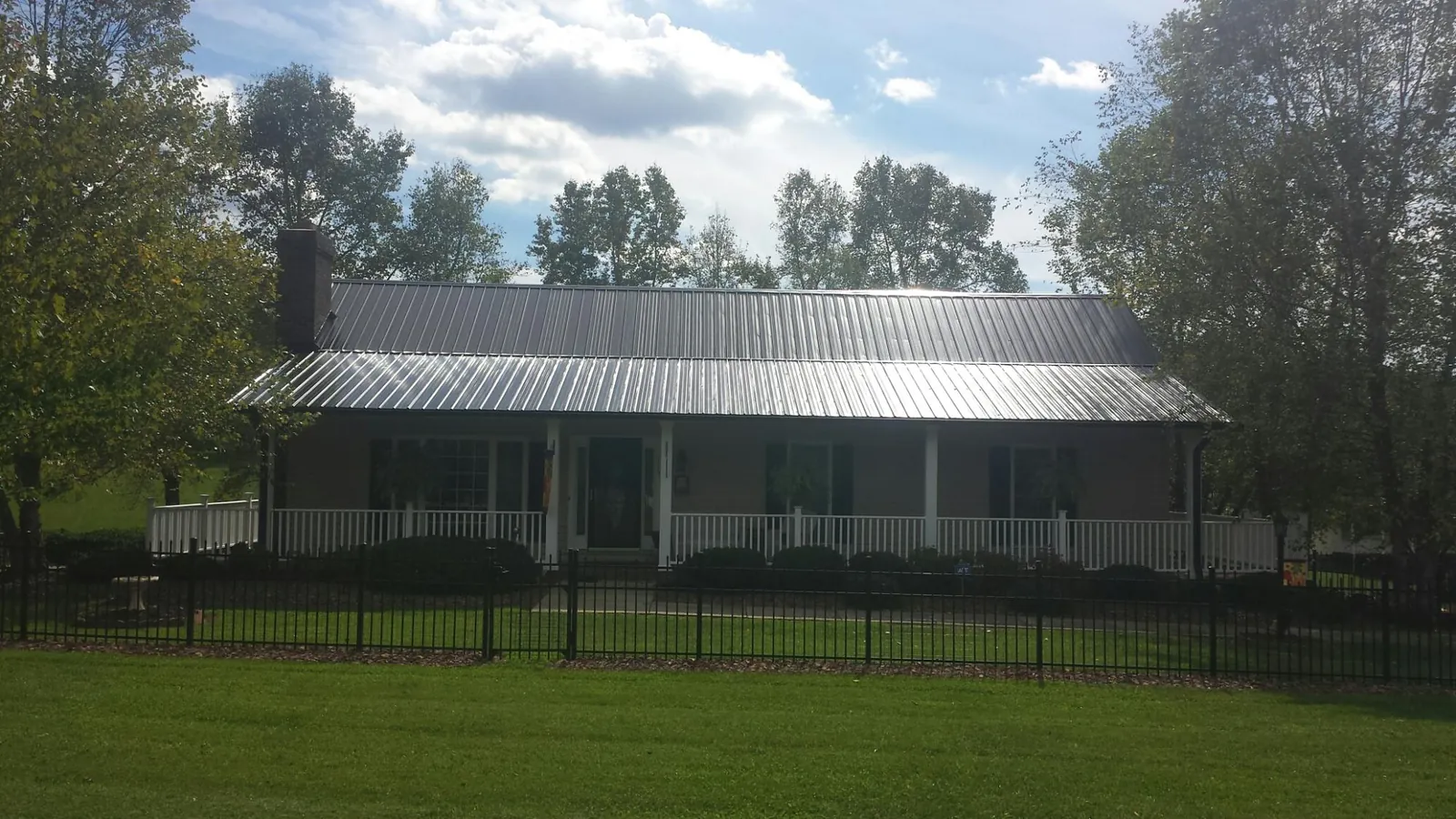 Gray metal roof on a brick ranch with a full width front porch — Gutter Guard Installation work by our crew in Cranston